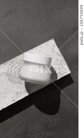 cream jar made of white frosted glass lies on a concrete pedestal against cream jar made of white frosted glass lies on a concrete pedestal against 106750699