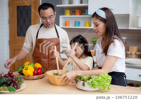 Happiness asian family with father, mother and daughter preparing cooking salad vegetable food. Happiness asian family with father, mother and daughter preparing cooking salad vegetable food. 106751220