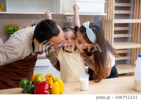 Happy family with father, mother and daughter in kitchen drinking milk in glass for healthy. Happy family with father, mother and daughter in kitchen drinking milk in glass for healthy. 106751221
