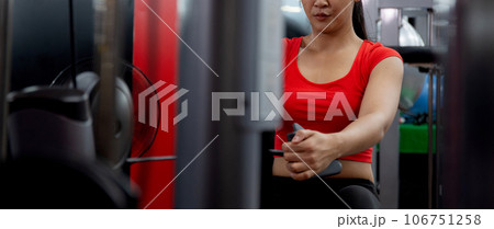 Young asian woman workout with strength training and determination with fitness gym machines. 106751258