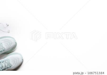 New light blue green female running shoes and headphones on emty white background. Stylish monochrome shoes for active people that incorporate new health technology. Top view New light blue green female running shoes and headphones on emty white background. Stylish monochrome shoes for active people that incorporate new health technology. Top view 106751384
