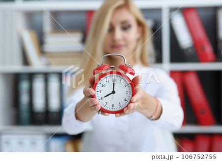 Smiling business woman holding in hand clock 106752755