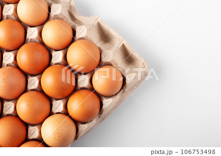 Chicken brown fresh raw eggs in an egg container on white background. 106753498