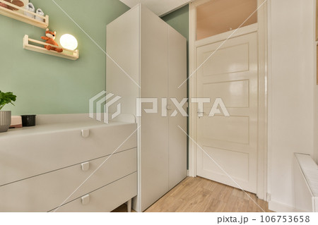 a room with green walls and white furniture on the left side of the room, there is an open door that leads to a a room with green walls and white furniture on the left side of the room, there is an open door that leads to a 106753658