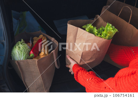 woman hand put bags with groceries shopping into cur trunk woman hand put bags with groceries shopping into cur trunk 106754161