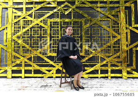 College graduate sitting in front of golden background at university Bangkok Thailand 106755685