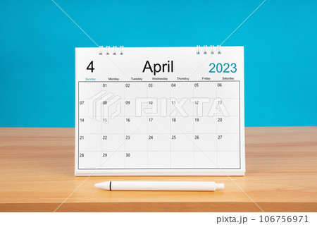 The April monthly desk calendar for 2024 year and pen on wooden table with blue color background. 106756971