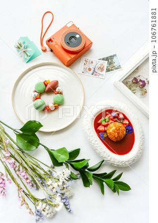Background with desserts, polaroid camera and flowers. Top view on white table Background with desserts, polaroid camera and flowers. Top view on white table 106761881