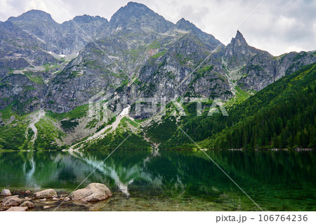 Amazing view on mountains range near beautiful lake at summer day. Tatra National Park in Poland. Panoramic view on Morskie Oko or Sea Eye lake in Five lakes valley Amazing view on mountains range near beautiful lake at summer day. Tatra National Park in Poland. Panoramic view on Morskie Oko or Sea Eye lake in Five lakes valley 106764236