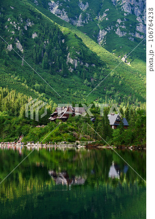 Spruce forest near blue lake in mountains. Tatra National Park in Poland. Panoramic view on Morskie Oko or Sea Eye lake in Five lakes valley. Nature landscape Spruce forest near blue lake in mountains. Tatra National Park in Poland. Panoramic view on Morskie Oko or Sea Eye lake in Five lakes valley. Nature landscape 106764238