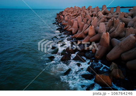 Waves break on concrete tetrapod breakwaters at sea coast. Protection from large waves. Baltic Sea coast at Wladyslavovo port at sunset 106764246