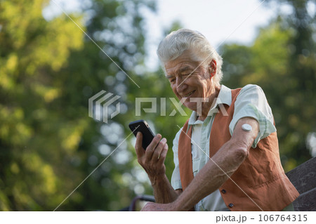 Senior diabetic man checking his glucose data on smartphone outdoors, in park. Senior diabetic man checking his glucose data on smartphone outdoors, in park. 106764315
