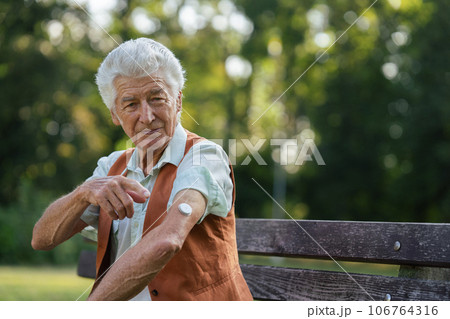 Senior man showing a sensor of continuous glucose monitor on his arm. 106764316