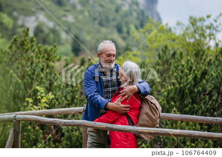 Senior tourists embracing on a wooden bridge during a hike in the autumn mountains. 106764409