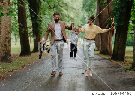 Young family with little son on walk in city park after work. 106764460