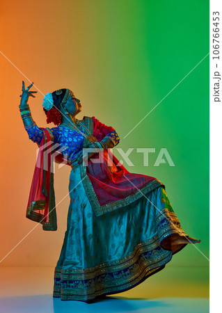 Indian culture. Mature, beautiful indian woman in traditional clothes, dress posing against gradient studio background in neon light 106766453