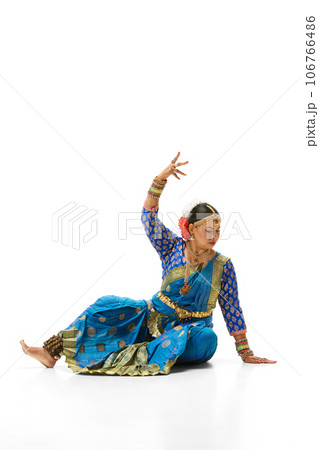 Beautiful mature indian woman in traditional dress dancing indian dance against white studio background Beautiful mature indian woman in traditional dress dancing indian dance against white studio background 106766486