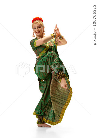 Beautiful woman in green dress dancing traditional indian dance bharatanatyam against white studio background Beautiful woman in green dress dancing traditional indian dance bharatanatyam against white studio background 106766525