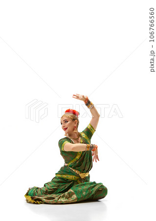 Following indian traditions. Beautiful woman in green dress dancing against white studio background 106766560