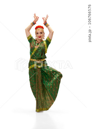Beautiful, elegant, young woman in traditional indian dress dancing against white studio background Beautiful, elegant, young woman in traditional indian dress dancing against white studio background 106766576