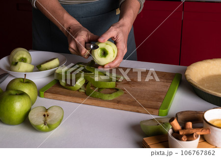 Woman is peeling apples to prepare apple pie in the kitchen. Authentic female hands peel an apple 106767862