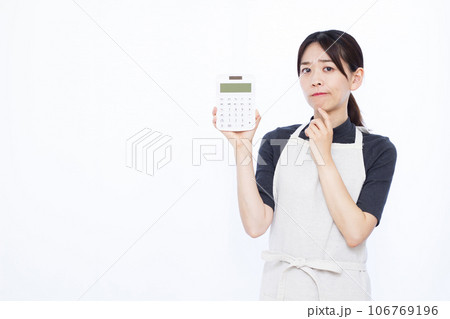 白い背景の前で電卓を持って悩んでいる30代の主婦 白い背景の前で電卓を持って悩んでいる30代の主婦 106769196
