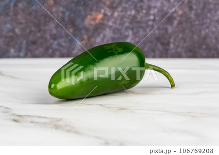 Close-up of a pod of green hot pepper on a light surface. 106769208
