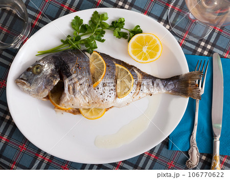 Top view of whole dorada baked with lemon served at plate with greens Top view of whole dorada baked with lemon served at plate with greens 106770622