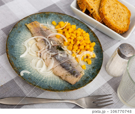 Sliced pickled herring fillet with corn and onions on plate Sliced pickled herring fillet with corn and onions on plate 106770748