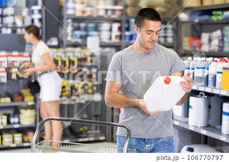 Interested young handyman choosing quality paint primer in store 106770797