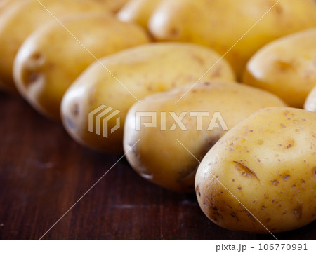 Closeup many potato tubers on wooden surface Closeup many potato tubers on wooden surface 106770991