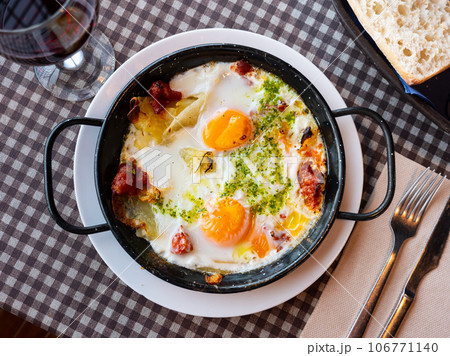 Traditional Riojan eggs with potatoes and sausages in iron pan 106771140
