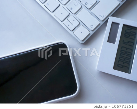 テーブルに置かれたキーボードと電卓とスマートフォン 106771251