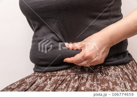 【お腹の肉を摘む主婦】 106774659