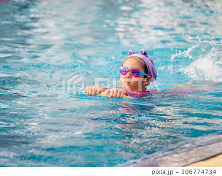 Asian child or kid girl wearing swimming suit to learning on swimming pool , learn and training swim on kick board Asian child or kid girl wearing swimming suit to learning on swimming pool , learn and training swim on kick board 106774734