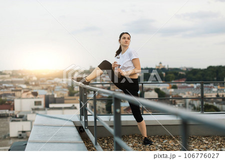 Lady with sports bottle having rest at handrails on terrace Lady with sports bottle having rest at handrails on terrace 106776027