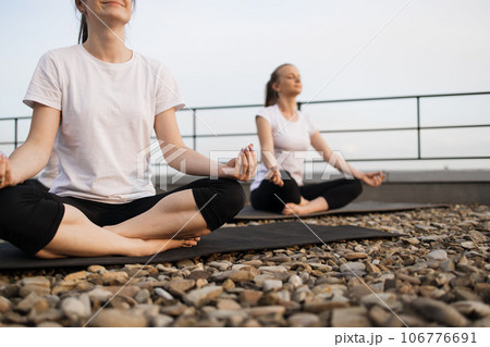 Females in lotus asana smiling in meditation under sunlight 106776691