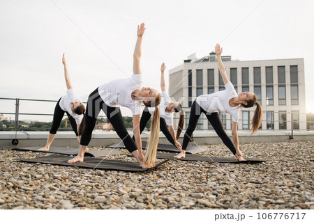 Yoginis standing in asana with raised hands outdoors 106776717