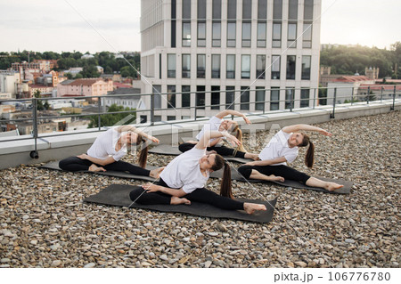 Sportswomen exercising seated asana in outdoor yoga practice Sportswomen exercising seated asana in outdoor yoga practice 106776780