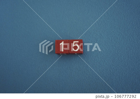 Wooden Viva Magenta cubes with number 15 on blue background close-up top view. Concept of date or time. White numbers 15 106777292