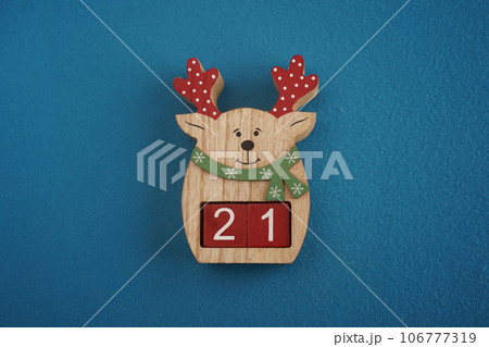 Festive wooden deer with Viva Magenta cubes 21 on blue background close-up top view. Christmas concept of date 106777319