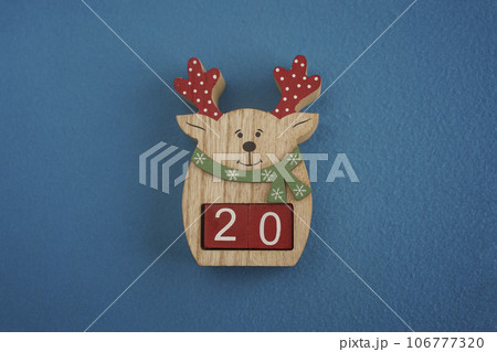 Festive wooden deer with Viva Magenta cubes 20 on blue background close-up top view. Christmas concept of date or time 106777320