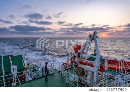 船のデッキから夕陽を眺めカメラのシャッターを切る観光客 船のデッキから夕陽を眺めカメラのシャッターを切る観光客 106777999