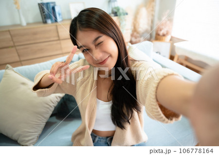 Pretty young asian female with big smile sitting at living room Pretty young asian female with big smile sitting at living room 106778164