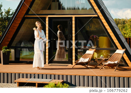 Cute woman standing on terrace of wooden cabin 106779262