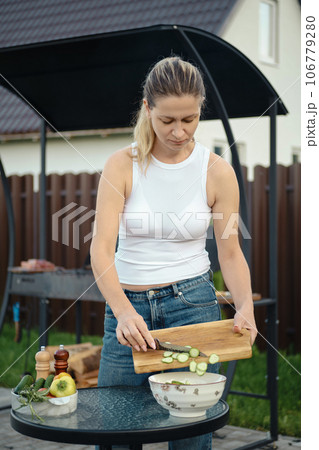 Woman adding sliced cucumber to a bowl 106779280