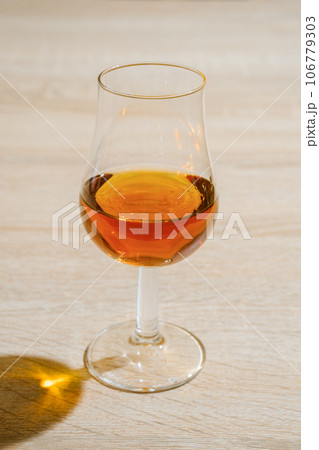 Tulip glass with cognac on wooden table Tulip glass with cognac on wooden table 106779303