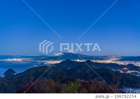 （静岡県）沼津アルプスと街灯りの向こうに雪化粧した富士山 106782254
