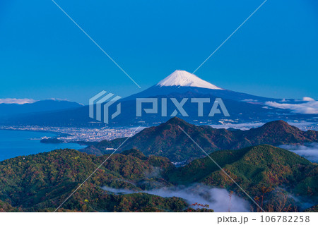（静岡県）沼津アルプスと街灯りの向こうに雪化粧した富士山 106782258