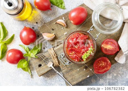 Healthy homemade fermented food. Sun-dried tomatoes in jar with spices and herbs. Home economics, autumn harvest preservation. 106782382